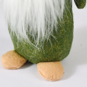 Detail of green felt Christmas gnome ornament with white beard and soft fabric texture