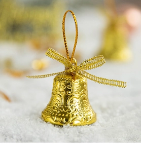 Macro shot of a golden Christmas bell with embossed patterns and mesh bow ornament