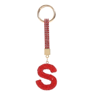 Detailed macro view of red crystal letter S keychain with gold metallic hardware