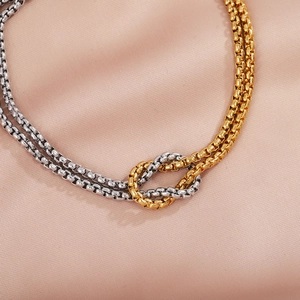 Detail of interlocking gold and silver beaded chains on elegant pink silk background