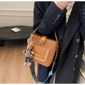 Detail of brown leather bucket bag with ethnic strap and cute rabbit pendant