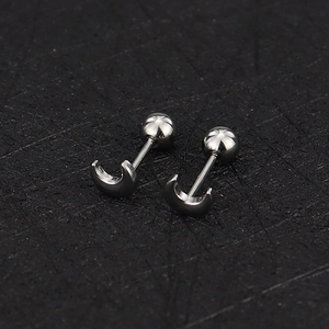 Macro view of silver stainless steel crescent moon cartilage earrings with screw back ball