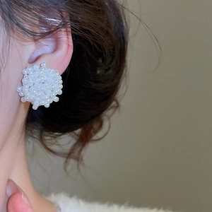 Gros plan détaillé de boucles d'oreilles fleurs en perles blanches sur le mannequin