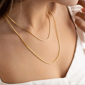 Close-up of golden box chain necklace showing intricate square links on skin