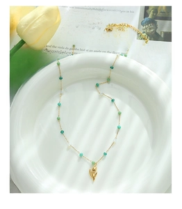 Detailed close-up of golden tulip pendant with emerald green and mint beads on a necklace