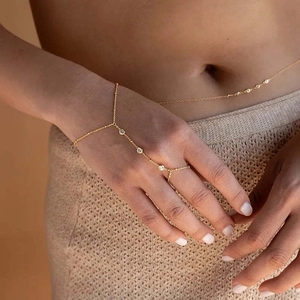 Macro view of gold plated finger ring bracelet set with white zircon stones on model