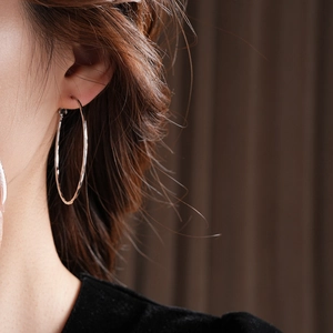 Grosse boucle d'oreille créole argentée avec texture martelée vue de profil sur mannequin