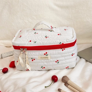 Close-up of quilted cherry print toiletry bag with red zipper and top handle detail