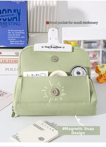 Detail of green canvas pencil case featuring front pocket and magnetic button closure