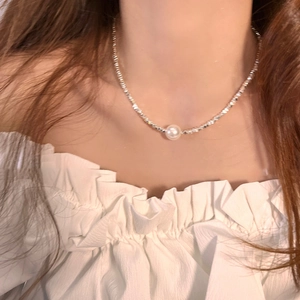 Elegant silver chain necklace with a white pearl pendant worn by a model on collarbone