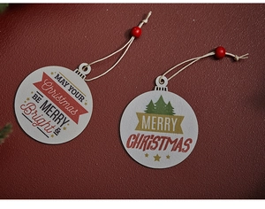 Dettaglio di ornamenti natalizi in legno con scritte festive su sfondo rosso intenso