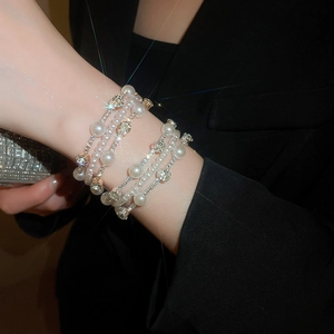 Detail of layered pearl and diamond bracelet with gold metal chains on wrist