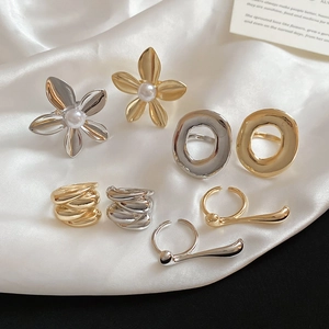 Flat lay of diverse minimalist floral and textured metallic rings on white silk fabric