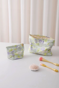 Detail of floral jacquard cosmetic bags in two sizes with gold flower-shaped zipper pulls