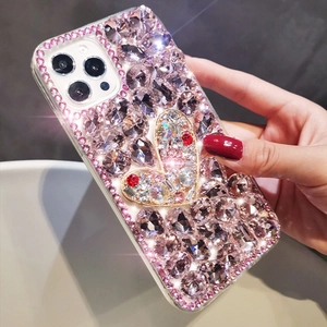 Close-up of luxury hand-held iPhone case with pink crystals and heart design detail