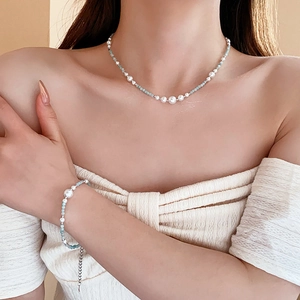 Détail de l'ensemble collier et bracelet en perles bleu clair sur un modèle en haut blanc