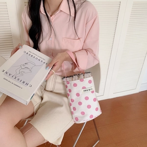 Close-up of pink polka dot canvas bucket bag with lace trim and ribbon handle