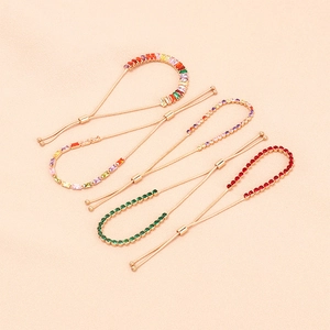 Bracciali dorati regolabili con zirconi colorati su sfondo rosa pastello