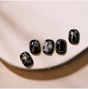 Vue macro d'autocollants pour ongles noirs avec papillon doré et motifs de nœuds