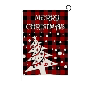Close-up of linen garden flag with red black plaid pattern and white Christmas tree