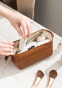 Dettaglio trousse in pelle PU marrone con ampia apertura e cerniera metallica dorata