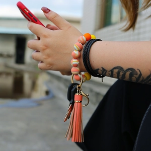 Close-up of orange silicone beaded wristlet keychain with leather tassel and gold ring