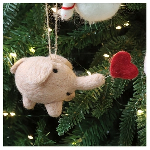Pink wool felt elephant ornament with red heart detail hanging on a Christmas tree