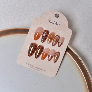 Macro shot of 3D shell patterns and leopard print with gold crosses on almond press-on nails