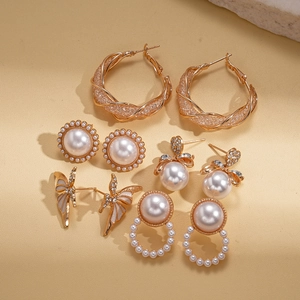 Ensemble de cinq paires de boucles d'oreilles dorées avec perles et strass sur beige