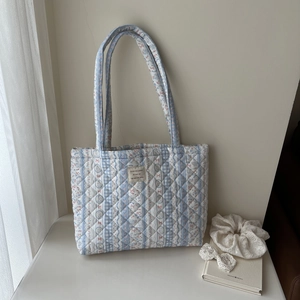 Detail of floral quilted tote bag with French label and soft cotton texture