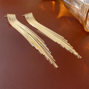 Macro shot of gold-plated long chain tassels on minimalist style dangling earrings