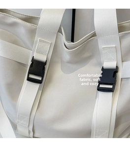 Detail of white canvas bag showing the durable fabric texture and adjustable black buckle