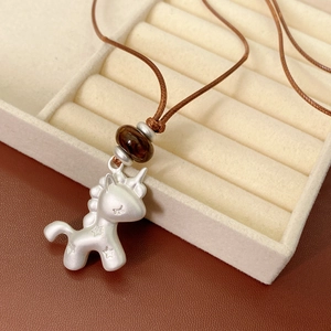 Vue détaillée du pendentif licorne argenté avec perle brune et cordon tressé