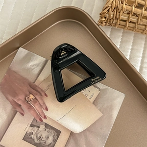 Detailed close-up of a black triangular acetate hair claw with gold Barrette La France text