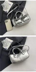 Detail view of silver metallic saddle bag with front pockets and adjustable strap