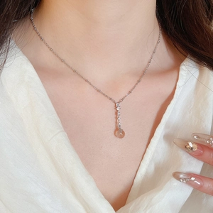 Close-up of elegant silver necklace with zircon pendant worn by a model in a white shirt