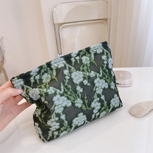 Detail of black mesh storage bag with green floral embroidery and zipper closure