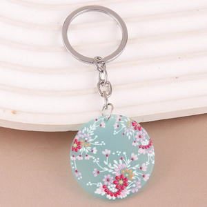 Detail of bohemian acrylic floral keychain with blue base and vibrant flower patterns