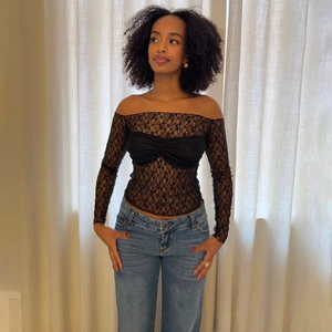 Détail d'un haut noir en dentelle transparente avec épaules dénudées sur un mannequin