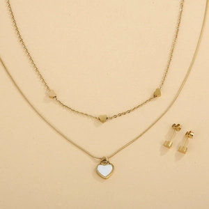 Detail of double-layer gold necklace with white shell heart pendant and matching studs