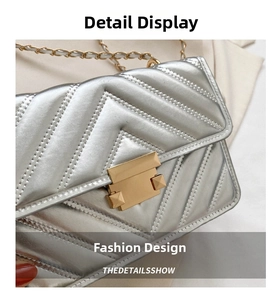 Detailed macro of silver quilted bag with gold hardware lock and chain strap