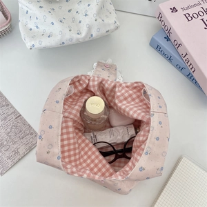 Detailed view of floral canvas bag with lace trim, pink inner grid, and button closure