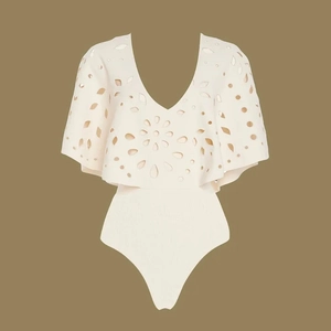 Detail of laser-cut floral patterns and ruffled cape sleeves on cream white bodysuit