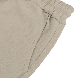 Detailed view of beige linen shorts featuring elastic waistband and functional side pockets