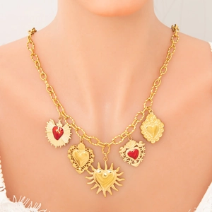 Close-up of gold chunky chain necklace with five unique heart-shaped charms on model