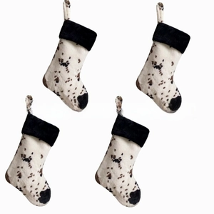Set of four plush cow print Christmas stockings with white faux fur and hanging loops