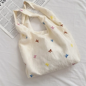 Macro detail of white tulle tote bag featuring colorful bow embroidery and pleated texture