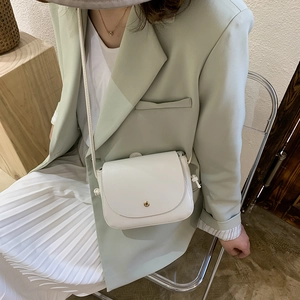 Minimalist white crossbody bag with gold buckle shown on a model in a fresh style
