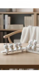 Detalle de seis figuras de gato en resina blanca con cascabeles sobre soporte de madera
