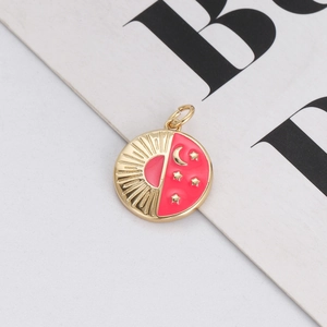 Detail of round gold pendant with pink enamel featuring celestial sun moon and stars
